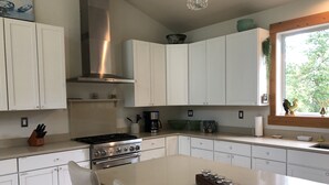 A modern kitchen with white cabinetry, a stainless steel stove, and a large island with a candle holder.