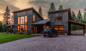 Une maison moderne à deux étages, dotée de grandes fenêtres et d’une allée gravillonnée.