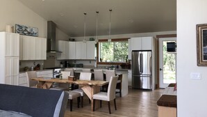 A modern kitchen with white cabinets, stainless steel appliances, and a dining area with a wooden table and chairs.