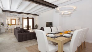 A modern dining area with a wooden table set for six, white chairs, and a central light fixture. - SANT SEBASTIA. Modern villa in Pollensa (Pollensa)