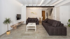 A modern living room with a sofa, coffee table, and TV. There is a staircase leading to another level. - SANT SEBASTIA. Modern villa in Pollensa (Pollensa)