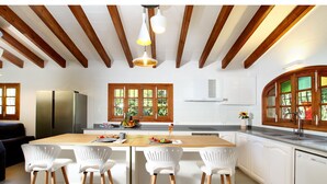 A modern kitchen with wooden beams, white cabinets, and a central island with bar stools. - JAUME RAMONA. Stunning newly renovated villa in a formidable setting (Pollensa)