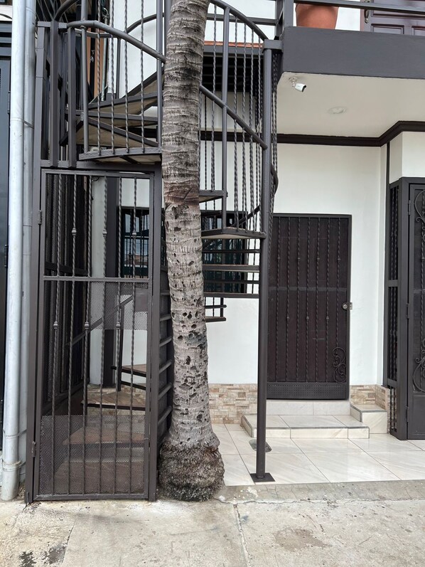 A gated entrance with a spiral staircase leading to a balcony.