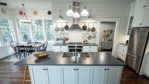 A modern kitchen with a large island, white cabinetry, and stainless steel appliances. - 5 Points Bungalow, Athens, GA (Athens)