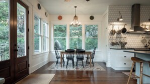 A kitchen with a dining table, chairs, and a bar stool. There are windows, a chandelier, and a stove. - 5 Points Bungalow, Athens, GA (Athens)