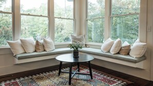 A bay window with multiple seats and a small table, surrounded by a patterned rug. - 5 Points Bungalow, Athens, GA (Athens)