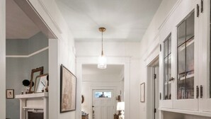 A hallway with a patterned rug, white cabinetry, and a fireplace. - 5 Points Bungalow, Athens, GA (Athens)