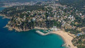 Vue aérienne d’une ville côtière avec une plage, un port de plaisance et des immeubles résidentiels.
