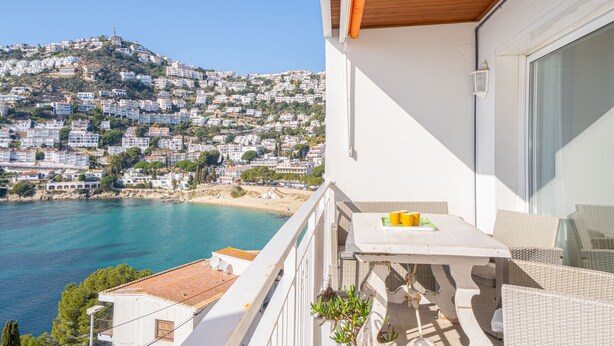 Un balcon avec une table et des chaises donnant sur une ville côtière.