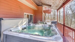 Un espace avec un bain à remous, une terrasse en bois et une vue sur les arbres.
