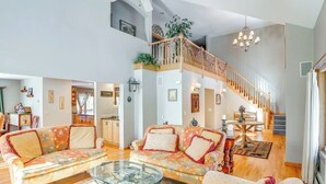 Un vaste espace de vie comprenant un grand canapé, une table basse en verre et un escalier menant à l’étage supérieur.