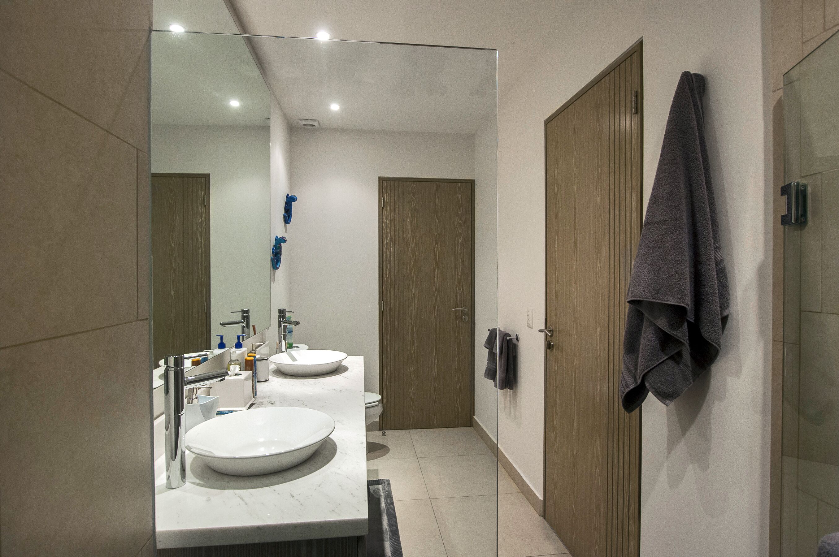Ein modernes Badezimmer mit zwei Waschbecken, einem großen Spiegel und Holztüren.