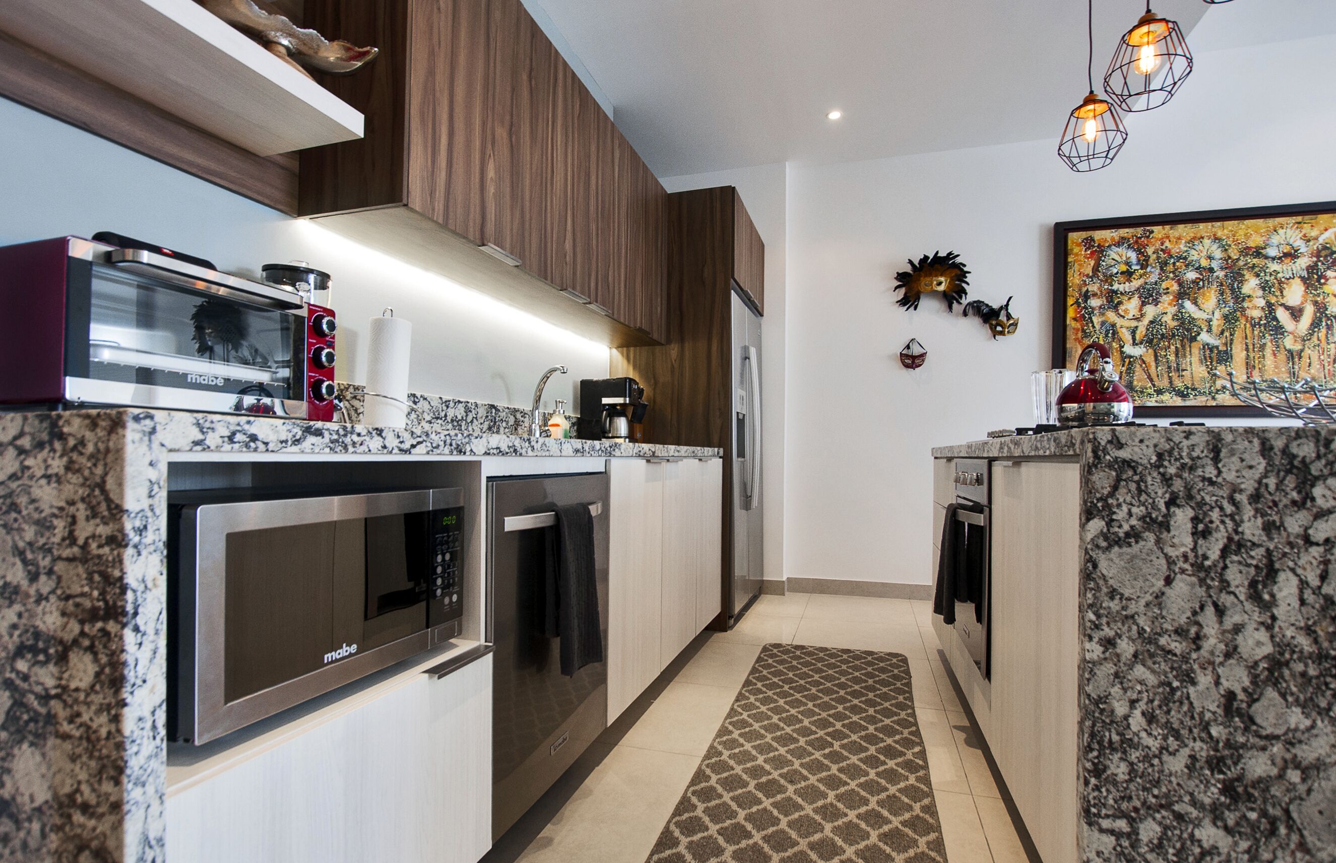 A modern kitchen with built-in appliances, wooden cabinets, and a patterned rug.