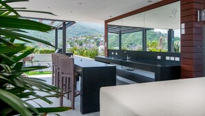 Un bagno moderno con uno specchio grande, un piano di lavoro nero e vista su un paesaggio rigoglioso.