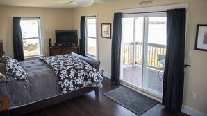 Een slaapkamer met een bed, een televisie en een balkon met uitzicht.
