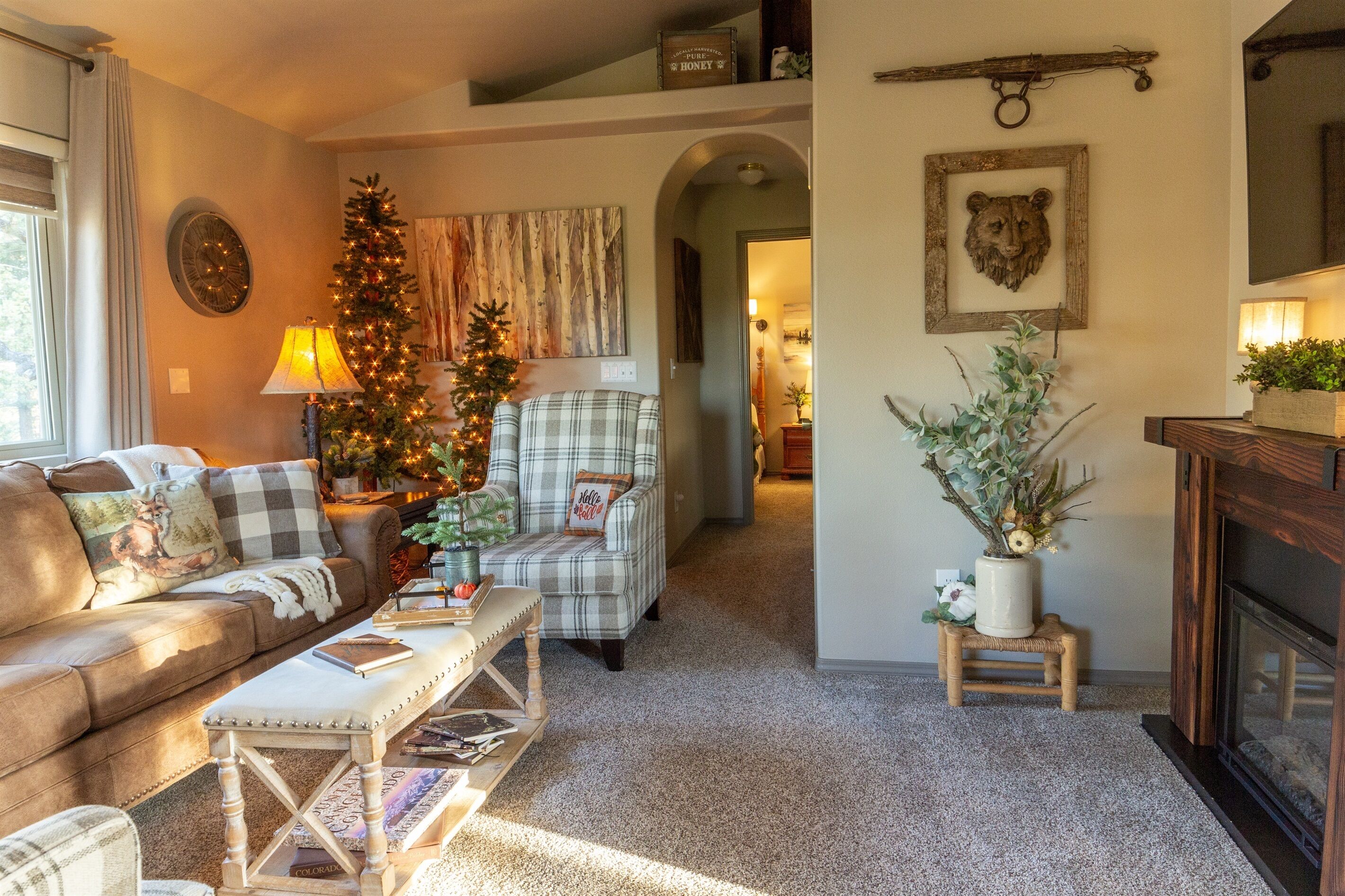 A cozy living room with a leather sofa, plaid armchair, and a Christmas tree.