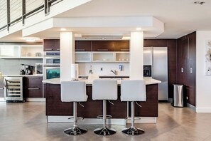 Una cocina moderna con una isla central, taburetes de bar y electrodomésticos integrados.