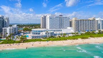 Un hôtel situé sur la côte, composé de plusieurs immeubles de grande hauteur, avec une plage de sable fin et une eau turquoise cristalline.