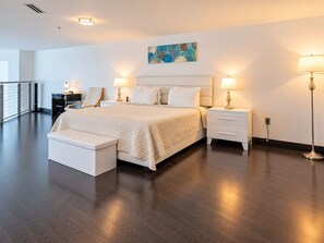 Une chambre d’hôtel moderne avec un grand lit, des tables de chevet, un banc et un tableau au mur.