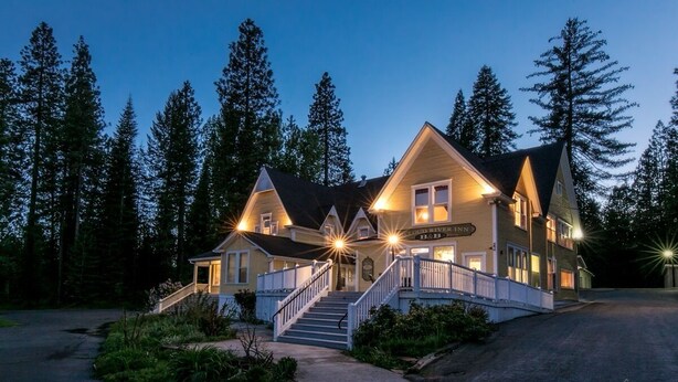 A lodge with a prominent staircase, a sign reading "Cloud River Inn," and a well-lit facade. - All inclusive Bed and Breakfast (McCloud)