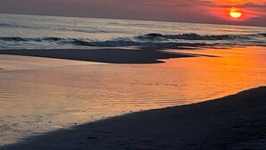 Un atardecer sobre una playa con olas y cielo despejado.