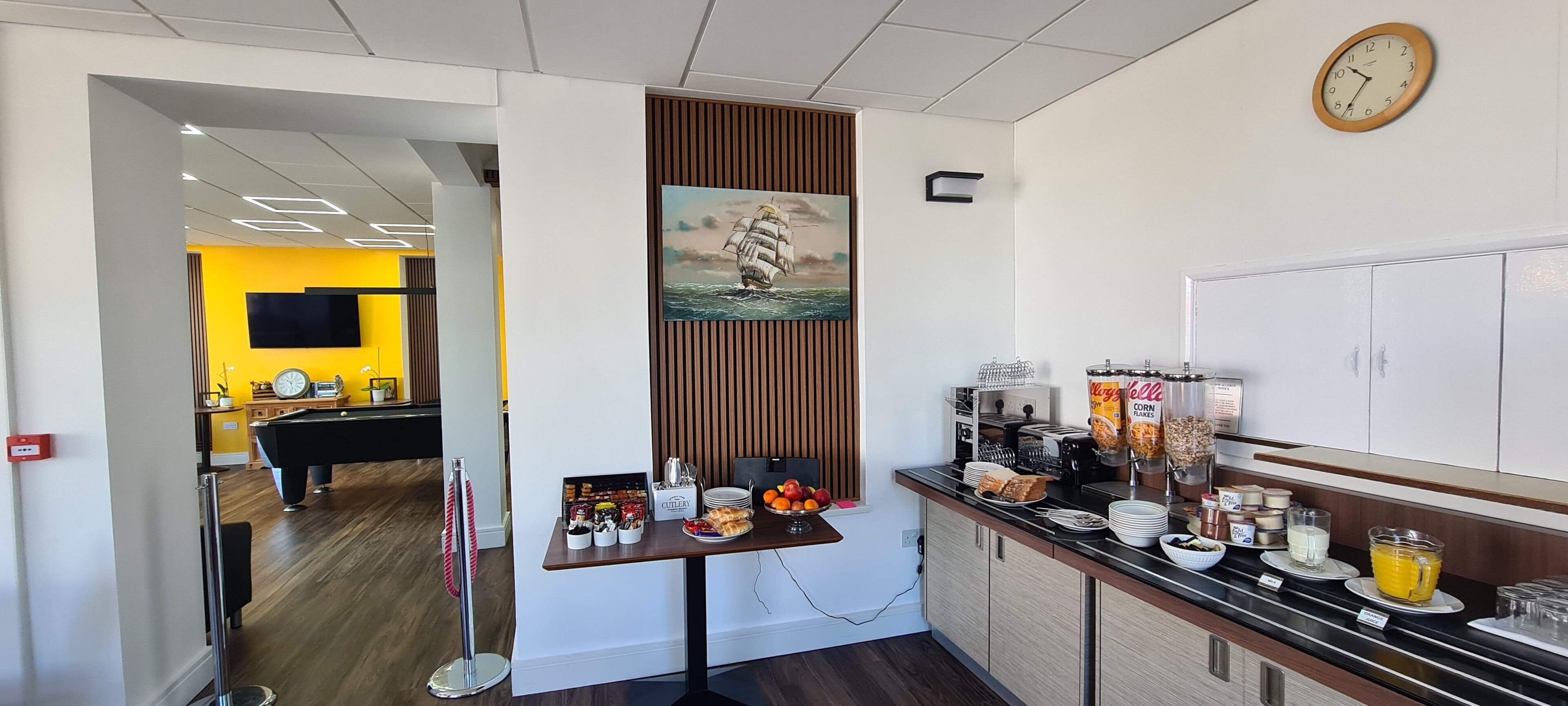 Eine moderne Küche mit einer Kaffeestation, einem Gemälde und einer Uhr an der Wand.