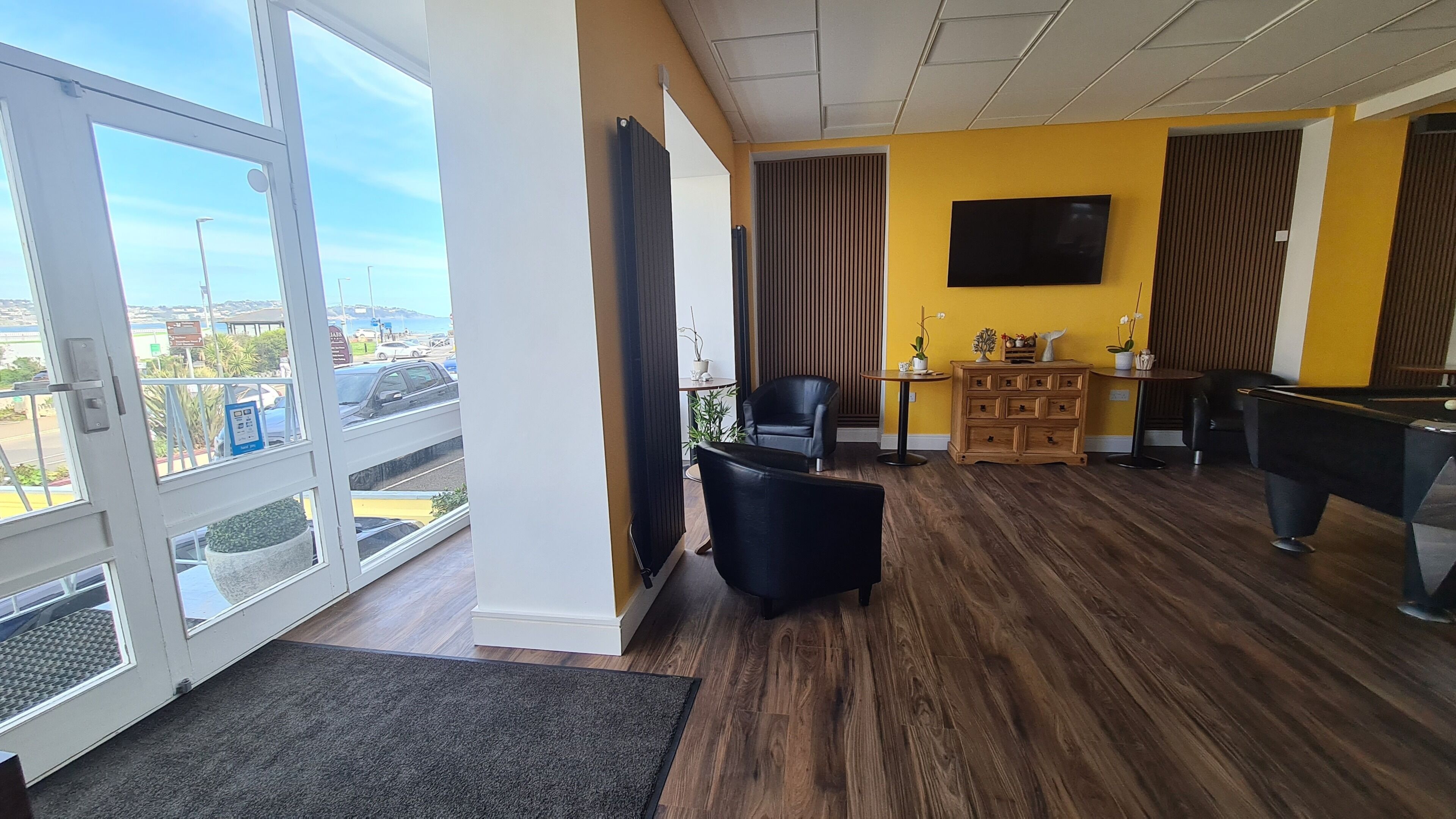 Una habitación con mesa de billar, una silla, un televisor y vistas a través de un ventanal.