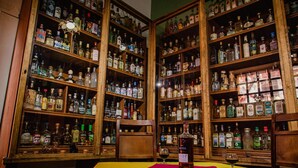 A bar area with wooden shelves stocked with various liquor bottles.