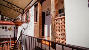 A staircase with a metal railing leading to a room with a brick wall and a window.