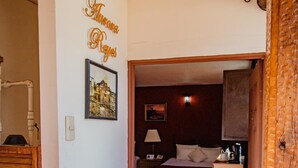 A hotel room with a bed, a desk, and a chair. There is a picture on the wall and a sign with the hotel's name.