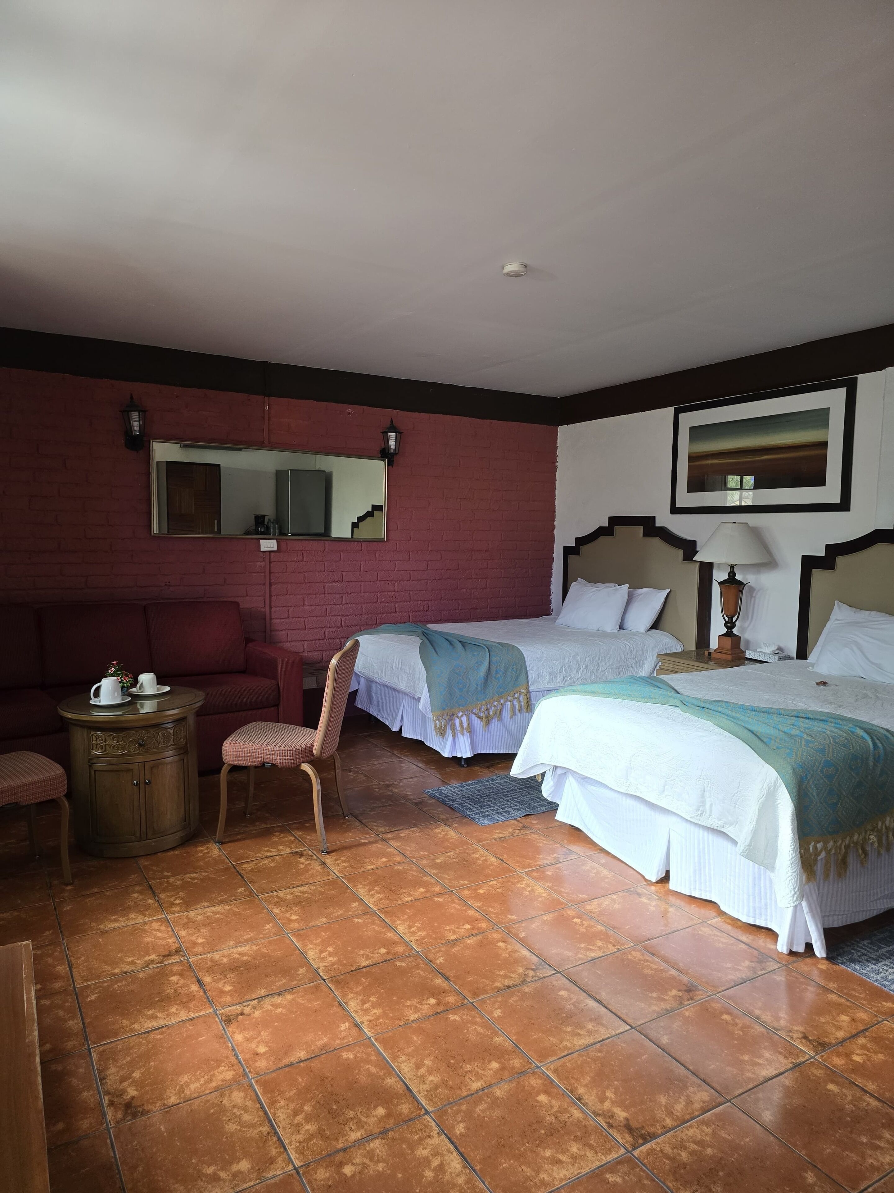 Habitació d'hotel amb dos llits, un sofà, una taula petita i una cadira.