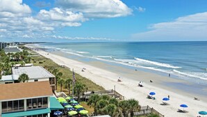 A beach with umbrellas, a flag, and a building with a green roof. - Beach House on Tidal Creek, Dock, Screen Porch, Easy Walk to Beach, Dog Friendly (Pawleys Island)
