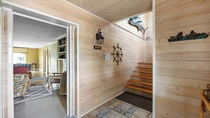 A wooden interior with a staircase, a wall-mounted ship's wheel, and a decorative fish sculpture. - Beach House on Tidal Creek, Dock, Screen Porch, Easy Walk to Beach, Dog Friendly (Pawleys Island)