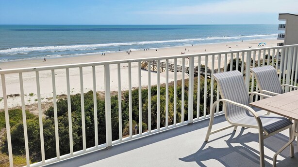 A balcony with a view of the beach, white railings, and a table with chairs. - Oceanfront Condo, Top Floor Ocean View, Elevator, Pool, Hot Tub, Beach Access (Pawleys Island)