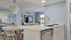 Une cuisine moderne dotée d’un îlot central, de meubles blancs et d’un lave-vaisselle encastré.
