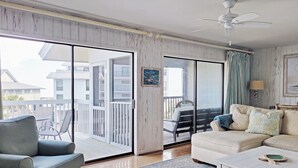 Un salon avec un canapé, une table basse et une vue sur le balcon extérieur.