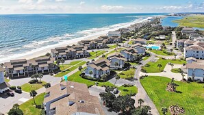 Un quartier résidentiel en bord de mer, avec des maisons modernes, une plage et un ciel dégagé.