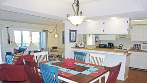 A dining area with a wooden table, blue chairs, and a red centerpiece.