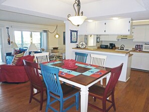 A dining area with a wooden table, blue chairs, and a red centerpiece. - Second Row Condo, Covered Parking, Creek Dock, 2 Pools, Access to 7-Mile Beach (Pawleys Island)