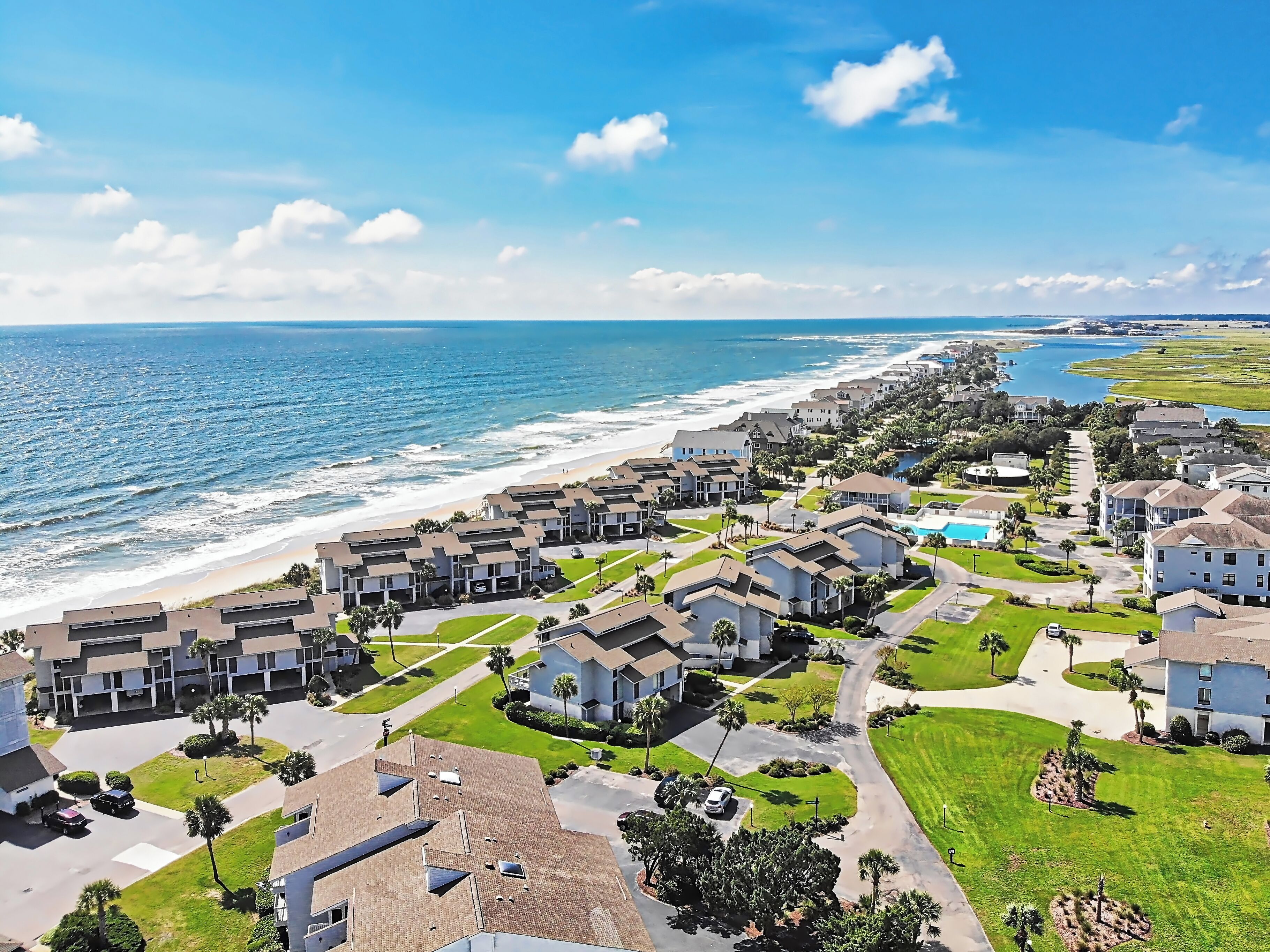 Zona residencial costera con casas modernas, una playa y cielo despejado.