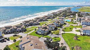A coastal residential area with modern houses, a beach, and a clear sky.