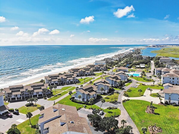 A coastal residential area with modern houses, a beach, and a clear sky.