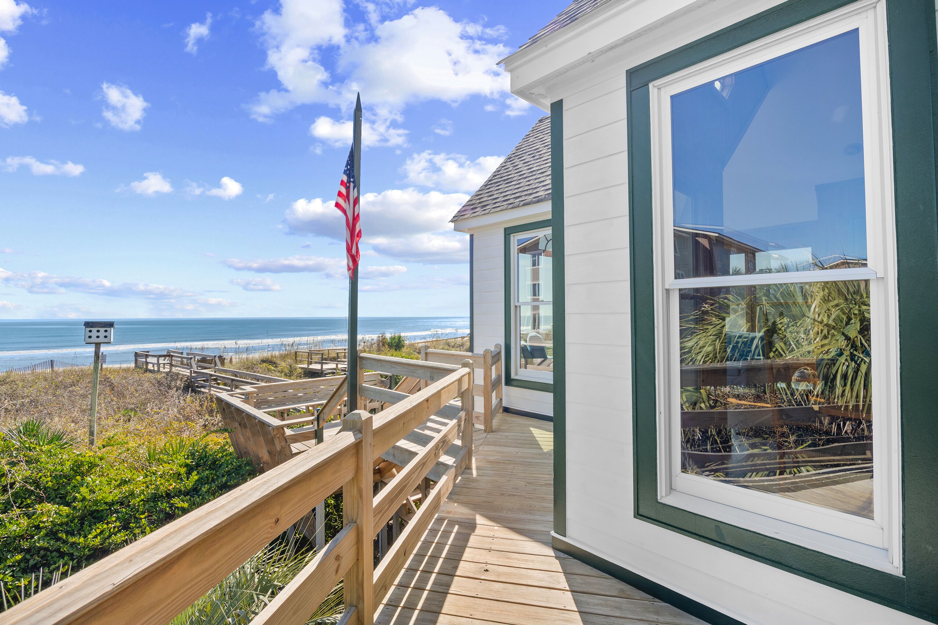 Eine Holzterrasse mit Blick auf Strand und Meer.