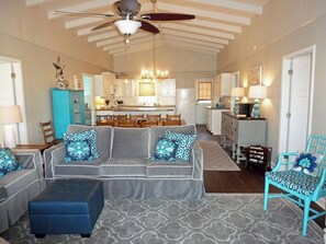 Relax in this stylish living room with a sofa, ottoman, and chair, plus a kitchen area with dining table.