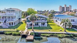 A waterfront property with a dock, a large house with a balcony, and a smaller house with a blue roof. - Canal Front Beach House, Screened Porch, 2 TV Dens, Dock, Short Block from Beach (Pawleys Island)