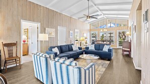 A spacious living area with a large sectional sofa, a round coffee table, and a wooden ceiling. - Canal Front Beach House, Screened Porch, 2 TV Dens, Dock, Short Block from Beach (Pawleys Island)