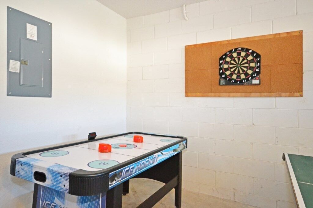 A room with a foosball table, a dartboard, and a door with a lock.