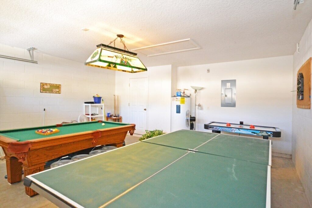 A billiards room with a pool table, a snooker table, and a foosball table.