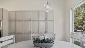 Un comedor con una mesa blanca, sillas y un centro de mesa decorativo.