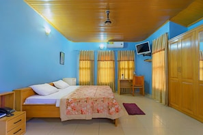 A bedroom with a bed, a desk, a wardrobe, a television, and a ceiling fan. - Okumah Executive Lodge & Conference Centre (Kintampo)